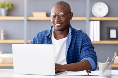 Serbest meslek hayatı. Laptop bilgisayarında çalışan Afrikalı Amerikalı bir adam, yeni bir proje yapıyor. Serbest çalışan, gözlük takan, gülümseyen ve uzaktan kumandalı işlerden hoşlanan,