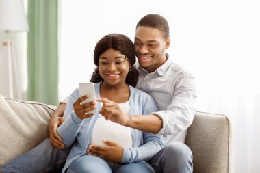 Siyahların evden alışveriş yapmasını beklemek, akıllı telefondan mobil uygulama kullanmak, kanepeye yaslanmak ve kucaklaşmak, cep telefonu ekranına bakmak ve gülümsemek, kopyalama alanı.