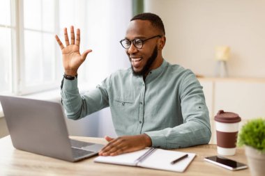 Afrikalı İşadamı, bilgisayarla çevrimiçi video görüşmesi yapıyor. Modern Ofisteki Webcam 'e merhaba diyor. Uzak İş İletişim Konsepti