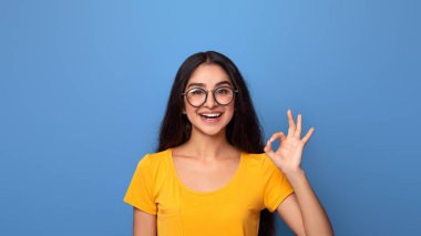 Her şey yolunda. Gözlüklü mutlu bir Hintli kadının portresi. El ve parmaklarıyla onay jesti yapıyor. Gülümsüyor, iyi olduğunu gösteriyor. Bayan iyidir.