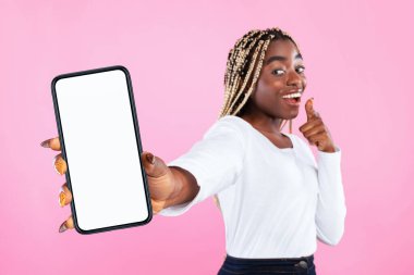 Elinde beyaz bir ekranla cep telefonu tutan neşeli Afro-Amerikan kadının portresi, cihazı gösteriyor. Modelleme, seçici odak, bulanık arkaplan için boş boş alanı olan Gadget