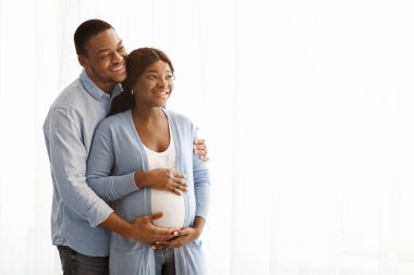 Neşeli Afro-Amerikan hamile çift beyaz arka plandan fotokopi çektiriyorlar, panorama. Siyahi bir kadın ve kocasının reklam izlemesini beklemekten mutluyum.