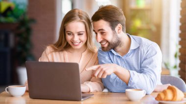 Güzel genç bayan ve erkek arkadaşı internette geziniyor ya da kahve dükkanında dizüstü bilgisayarda film izliyorlar. Modern bilgisayarlı sevgililer şehir kafesinde harika vakit geçiriyorlar.