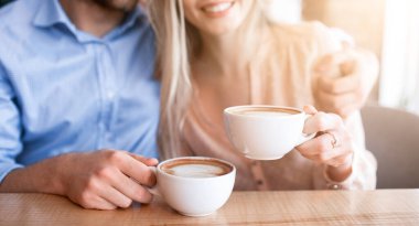 Kahve içip kafe 'de kucaklaşan romantik çift manzarası. Tanınmayan genç bir kadın ve sevgilisi restoranda sarılıp sıcak içeceklerin tadını çıkarıyor, birlikte öğle yemeği yiyorlar.