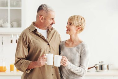Aşk, romantizm ve ilişkiler, sabah kahvaltısı. Mutlu son sınıf öğrencisi erkek ve kadın sıcak içeceklerle bardaklarını tokuşturur.