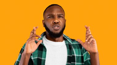 Bana şans dile. Siyah adamın parmakları çatık ve sarı arka planda dikilen rüya pozuna odaklanmış. Batıl inanç kavramı. Panorama, Stüdyo Çekimi
