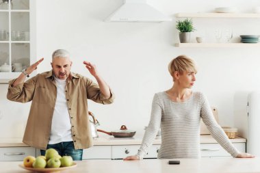 Kavga, yanlış anlaşılma ve evde çatışma. Kızgın, agresif, olgun, beyaz bir adam üzgün karısına bağırıyor ve küfrediyor. Mutfak içi, boş alan tartışmalarını dinlemeyin.