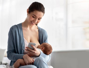 Mutlu Genç Anne, yeni doğmuş bebeğini emzirirken akıllı telefon kullanıyor, cep telefonunda gülümseyen kadın, yeni uygulamalara bakıyor ya da evde emziren çocuğu emzirirken internetten alışveriş yapıyor, boşluğu kopyalıyor.