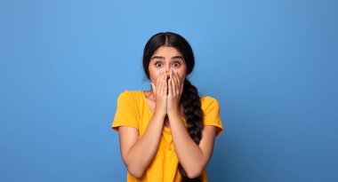 İnsanlar, İnsan Duyguları ve Duyguları Konsepti. Şaşırmış Hintli kadının portresi ağzını kapatıyor ve hayranlıkla kameraya bakıyor, mor stüdyo arka planında izole edilmiş.