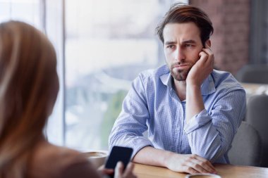 Gadget aşırı kullanımı konsepti. Sıkıcı genç adamın sıkıcı bir randevusu vardı, kız arkadaşı şehir kafesinde akıllı telefona sıkışmıştı. Milenyum kadını alet bağımlılığından muzdarip, erkek arkadaşıyla konuşmuyor.