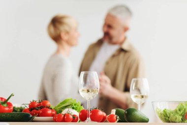 Mutlu çift, modern mutfakta romantik dans, gülen karı koca yıldönümünü kutluyor, hassas anın tadını çıkarıyor, evde eğleniyor. Salata ve şarap için taze taze sebzeler.