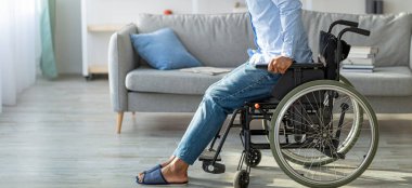 Evinde tekerlekli sandalyeden kalkmaya çalışan siyahi bir adam var. Engelli Afrikalı bir adam yürümeye çalışıyor, içeride bacakları için egzersiz yapıyor.