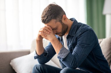 Oturma odasındaki koltukta oturan depresyondaki orta yaşlı bir adam, karantina sırasında elini uzatıyor, ya da yalnızlık, fotokopi odası, ev içi sıkıntısı çekiyor.