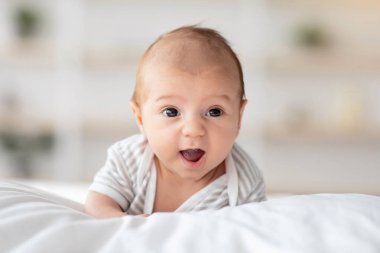 Karnında tatlı bir bebeğin yatakta yatışı, beyaz çarşafların üzerinde dinlenen komik bir bebeğin portresi, fotokopi alanı olan seçici bir odak noktası.