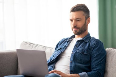 Modern dizüstü bilgisayar kullanan, evde yarı zamanlı işi olan, orta yaşlı bir adam. Başarılı sakallı adam film izlerken ya da defterde sohbet ederken, oturma odasında kanepede otururken.