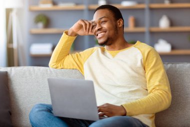 Mutlu bir Afro-Amerikan erkeği hafta sonunun tadını çıkarıyor, rahat bir oturma odasında kanepede oturuyor ve dizüstü bilgisayar kullanıyor, hayal kuruyor ve fotokopi odasına bakıyor. İnternette film arayan pozitif siyah adam