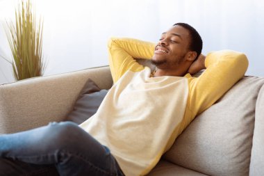 Memleketteki kanepeye yaslanıp fotokopi çeken neşeli Afro-Amerikalı adam. Yakışıklı genç siyah adam kanepeye oturmuş, gözleri kapalı, başarılı bir gelecek düşlüyor, iç mekan, oturma odası.