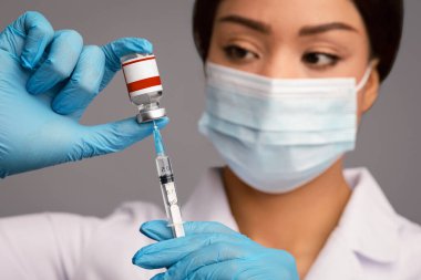 Coronavirus bağışıklığı. Mavi lateks eldivenler ve koruyucu tıbbi maske takan profesyonel terapist bayandan enjeksiyon için şırıngayla Covid-19 aşısı alan siyah kadın doktor.