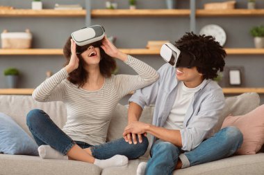 Olumlu insan duyguları, online sanal dijital oyun covid-19 salgını sırasında. Muhteşem gülümseyen bin yıllık Afro-Amerikan erkek ve kadın video gözlüklü sanal dünyada oturma odasının içinde, boşluğu kopyalayın.