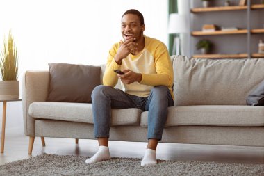 Evde televizyon izliyordum. Mutlu Afrikalı Amerikalı adam dinleniyor, uzaktan kumandayla kanal değiştiriyor ve gülümsüyor, boşluk. Zenci adam hafta sonunun tadını çıkarıyor, oturma odasında televizyon seyrediyor.