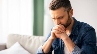 Evdeki kanepede oturmuş, elleri yere yaslanmış, üzgün, sorunları olan orta yaşlı üzgün bir adamın yakınlaşması, kopya odası. Yalnızlık, depresyon, akşamdan kalma konsepti.