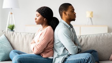Evdeki kanepede sırt sırta oturan siyah adam ve kadın üzgün. Afrikalı Amerikalı genç çift kavgadan sonra üzülüyor, ilişkilerde zorluklar ya da kriz yaşıyor, boş alan