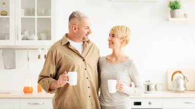 Sabahları evde birlikte sıcak kahve içeriz, iki kişilik kahvaltı yaparız. Mutlu, olgun bir adam ve çay bardaklarıyla birbirlerine bakıp, minimalist bir mutfak içinde beyaz arka planda konuşuyorlar.