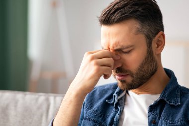 Orta yaşlı sakallı bir adam, baş ağrısı çekiyor, koltukta oturuyor ve burun köprüsüne dokunuyor, fotokopi çekiyor. Sıkıntılardan ya da depresyondan muzdarip, hayal kırıklığına uğramış insanların yakınlaşması, kopyalama alanı