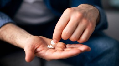 Tedavi, ilaç, ilaç, hap, vitamin, takviye konsepti. Avucunda birkaç hap tutan tanınmamış bir adam, kesilmiş. Erkek eli ilaçla yakın çekim