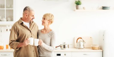 Aşk, romantizm ve ilişkiler, sabah kahvaltısı covid-19 salgını. Mutlu son sınıf öğrencisi erkek ve kadın sıcak içeceklerle bardaklarını tokuşturur.