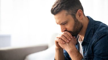 Düşünceli, sakallı, orta yaşlı bir adamın evdeki koltukta oturması, yere bakması, üzgün bir adamın sorun yaşaması, kopyalama alanı. Yalnızlık, depresyon, akşamdan kalma konsepti.