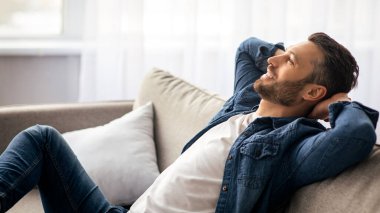 Kaygısız sakallı adamın evdeki kanepede rahat rahat oturup fotokopi çekilen yere ve manzaraya bakması. Mutlu orta yaşlı bir adam oturma odasında kanepede dinleniyor ve refah içinde bir hayat hayal ediyor.