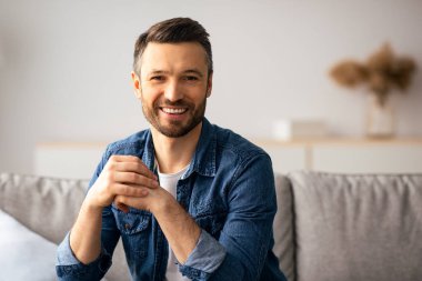 Yakışıklı, orta yaşlı, sakallı bir adam. Oturma odasında poz veriyor, kameraya gülümsüyor. Hafta sonu dinlenen mutlu beyaz adam, hayatının tadını çıkarıyor. Yurtiçi yaşam tarzı kavramı