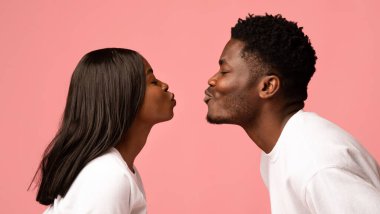 Beyaz elbiseli Afro-Amerikan çifti öpmenin yan görüntüsü. Pembe stüdyo arka planı, yakın çekim fotoğrafı, panorama. Aşk, sevgi, duygular, ilişkiler konsepti