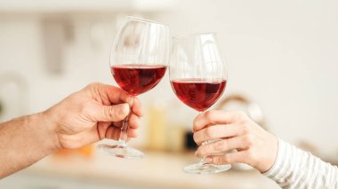 Tatil selamları, evde randevu ve romantik bir akşam. Ev hayatı ve yıldönümü. Yetişkin Avrupalı erkek ve kadın bardakları minimalist mutfağın içinde kırmızı şarap, boş alan, kırpılmış