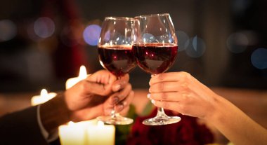 Hands Clinking Glasses Of Red Wine During Romantic Date In Restaurant. Cropped, Panorama