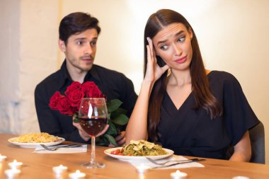 Bad Date. Young Couple Having Unsuccessful Meeting In Restaurant, Funny Disappointed Shoked Woman Feeling Embarrassment Covering Face, Man Giving Her Bouquet Of Red Roses