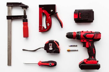 Beyaz arka planda çeşitli bina araçları, üst manzara. Elektrikli matkap, cetvel, kıskaç, tornavida, düz yatak. İş araçları, tamir için inşaat araçları