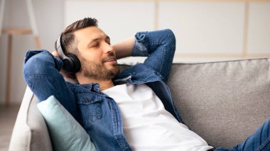 Rahatlama zamanı. Müzik dinleyen, fotokopi çeken, yakın çekim yapan, kablosuz kulaklıklı, orta yaşlı yakışıklı bir adam. Kulaklık takmış, gözleri kapalı, oturma odasında koltukta dinlenen mutlu bir adam.