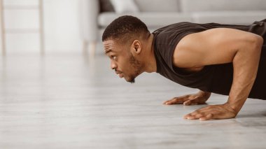 Atletik siyahi adam evde şınav çekerek egzersiz yapıyor. Vücut geliştirme, Erkek Fitness Eğitim Konsepti. Adam şınav egzersizi yapıyor. Güç egzersizi. Yan Görünüm, Boşluğu Kopyalayan Panorama