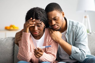 Negatif hamilelik testi olan üzgün siyah bir çift evdeki kanepede oturuyor, kucaklaşıyorlar ve sınava bakıyorlar, boş alan. Hüsrana uğramış Afrikalı Amerikalı kadın ve erkek kısırlık sorunu yaşıyor.