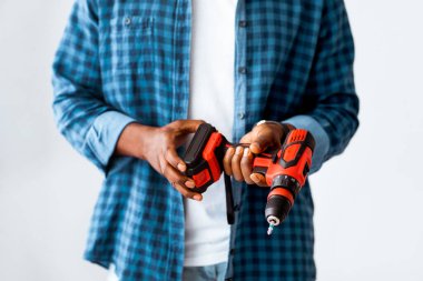 Montaj için araç gereç ve aksesuarlar. Siyah adam elinde elektrikli tornavida, beyaz arka planda duruyor. Mobilya ya da yenileme dairesi kurun, ev konseptini tamir edin