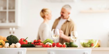 Mutlu çift, modern mutfakta romantik dans, gülen karı koca yıldönümünü kutluyor, hassas anın tadını çıkarıyor, evde eğleniyor. Salata ve şarap için taze taze sebzeler.