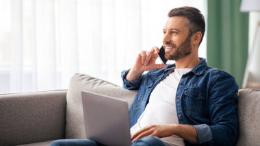 Neşeli, yakışıklı, orta yaşlı, sakallı bir adam hafta sonu evde tek başına eğleniyor, dizüstü bilgisayar kullanıyor, arkadaşlarıyla veya sevgilileriyle cep telefonunda sohbet ediyor, kanepede oturuyor, fotokopi odasına bakıyor.