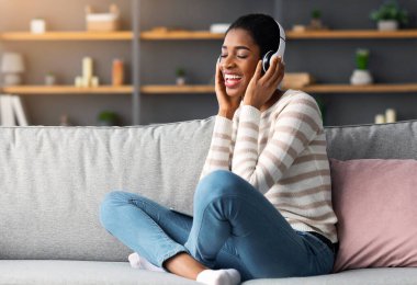 Yurtiçi Hobi. Neşeli Afrikalı Amerikalı Kadın Evde Kablosuz Kulaklıkla Müzik Dinliyor, Pozitif Siyah Kadın Kapalı Gözlerle Koltukta Oturuyor, Favori Çalma Listesinin keyfini çıkarıyor, Kopyalama Alanı