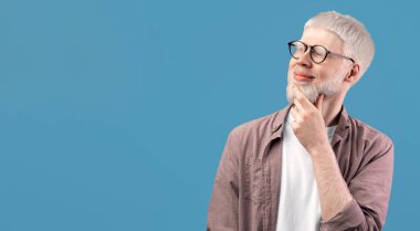 Düşünceli albino adam karar vermeyi düşünüyor, turkuaz stüdyo arka planındaki boşluğa bakıyor. Soluk tenli, beyaz saçlı, düşünceli sakallı adam umut ediyor, hayal ediyor, seçim yapıyor.