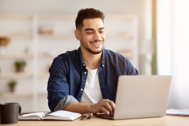 Evinden dizüstü bilgisayarda çalışan, klavyede yazan, e-posta gönderen, kopyalayan neşeli Arap adam. Çalışma masasında oturup iş arkadaşlarıyla sohbet eden mutlu bir orta doğulu.