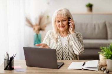 Telefonla konuşan hoşnutsuz olgun bir kadın bilgisayarla ya da evde oturan internet bağlantısıyla sorun yaşıyor. Memnun olmayan Bayan Müşteri Yardım Hattı Servisini Çağırıyor ve Şikayet Ediyor