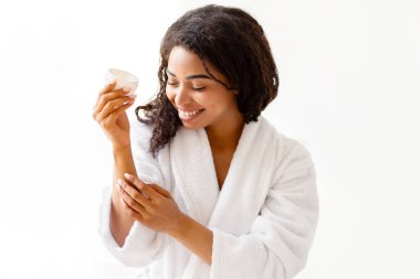 Cilt bakımı. Genç siyahi kadın, evdeki modern banyoda banyo yaptıktan sonra cildini ve vücudunu nemlendiriyor. Şımartma, Güzellik ve Sağlık