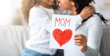 El yapımı hediye kartıyla neşeli siyah kız annesine sarılıyor, sevgili kızını Anneler Günü 'yle selamlıyor, anneciğini kucağında tutarken, anneler gününü kutluyor.